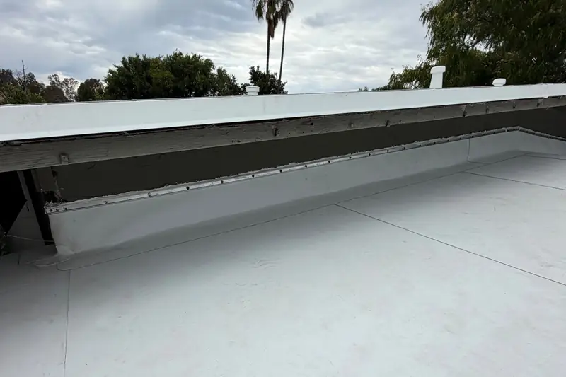 Finished white TPO flat roof on a home in Pacheco, CA, with trees and sky behind it