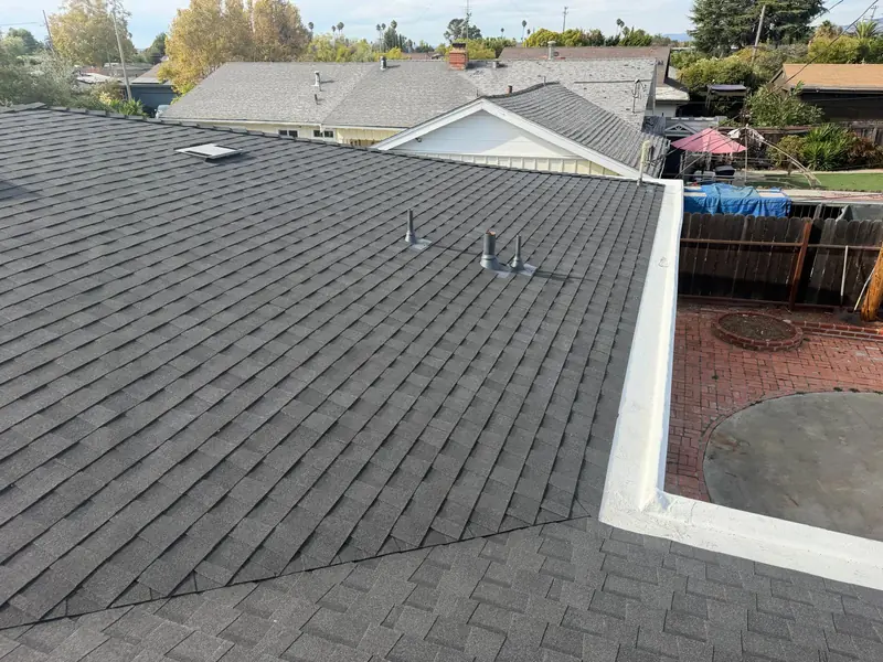 A finished gray shingle roof with a white edge, over a brick patio