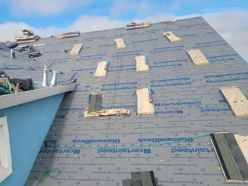 CertainTeed DiamondDeck underlayment covering a roof deck, with shingle bundles staged on top